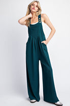 This Solid Sleeveless Wide Leg Jumpsuit boasts a square neckline, button adjustable straps, and a front bib pocket. The added pleats provide intricate detailing and there are also two side hip pockets. Made with 93% polyester and 7% spandex for a comfortable, stylish fit.