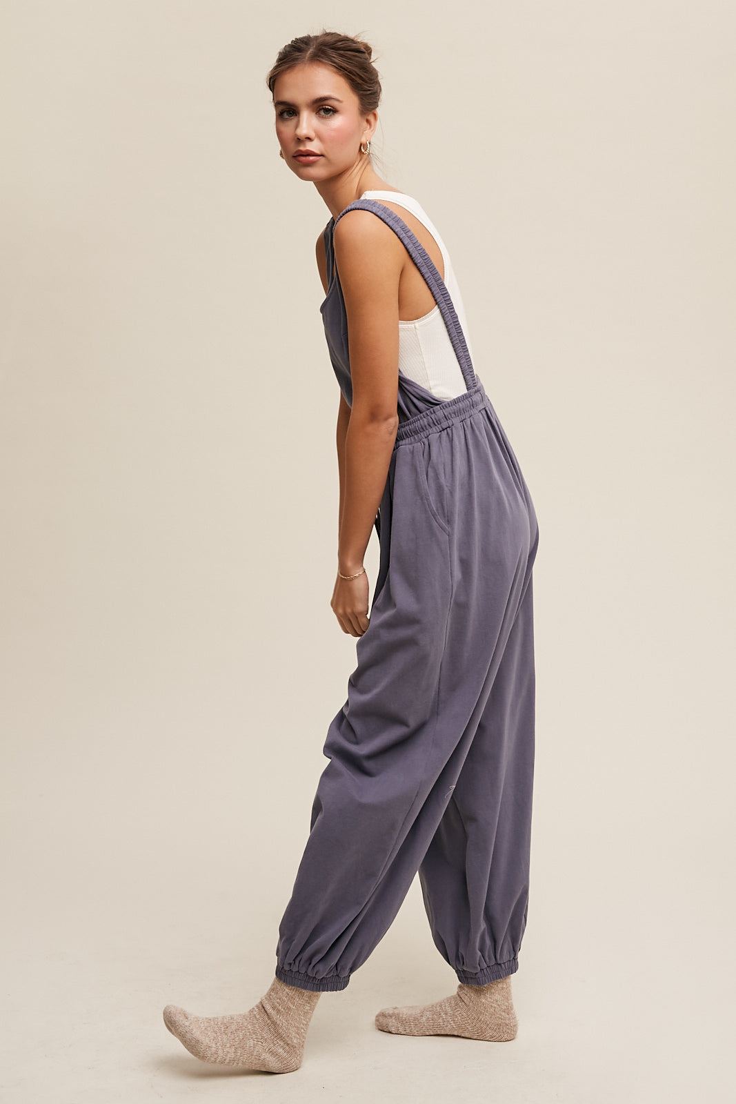 This Tank and Jogger Pants Open Back Knit Jumpsuit features a round neck, elastic shoulder strap, drawstring waist with tie string, and pockets on the pants. Made from 100% cotton in a charcoal color, the jumpsuit is finished with an elastic hem for a comfortable and stylish fit.