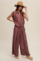 Consisting of a button down top and pleated wide leg pants, this set features a collared neck, short sleeves, and an elastic hem. The pants are designed with wide legs, pockets on the side seam, an elasticized drawstring waist with a tie string, and a clean hem. Made with 45% Rayon, 37% Tencel, and 18% Nylon, this set is available in Red Bean.