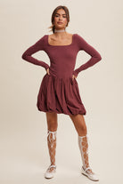 This dress features a square neckline, long sleeves, and a bubble skirt with a built-in romper liner. The top and shorts have a fitted, stretched design, and the skirt is made of cotton with a balloon layer. It comes in the color grape and is composed of 76% nylon and 24% spandex.