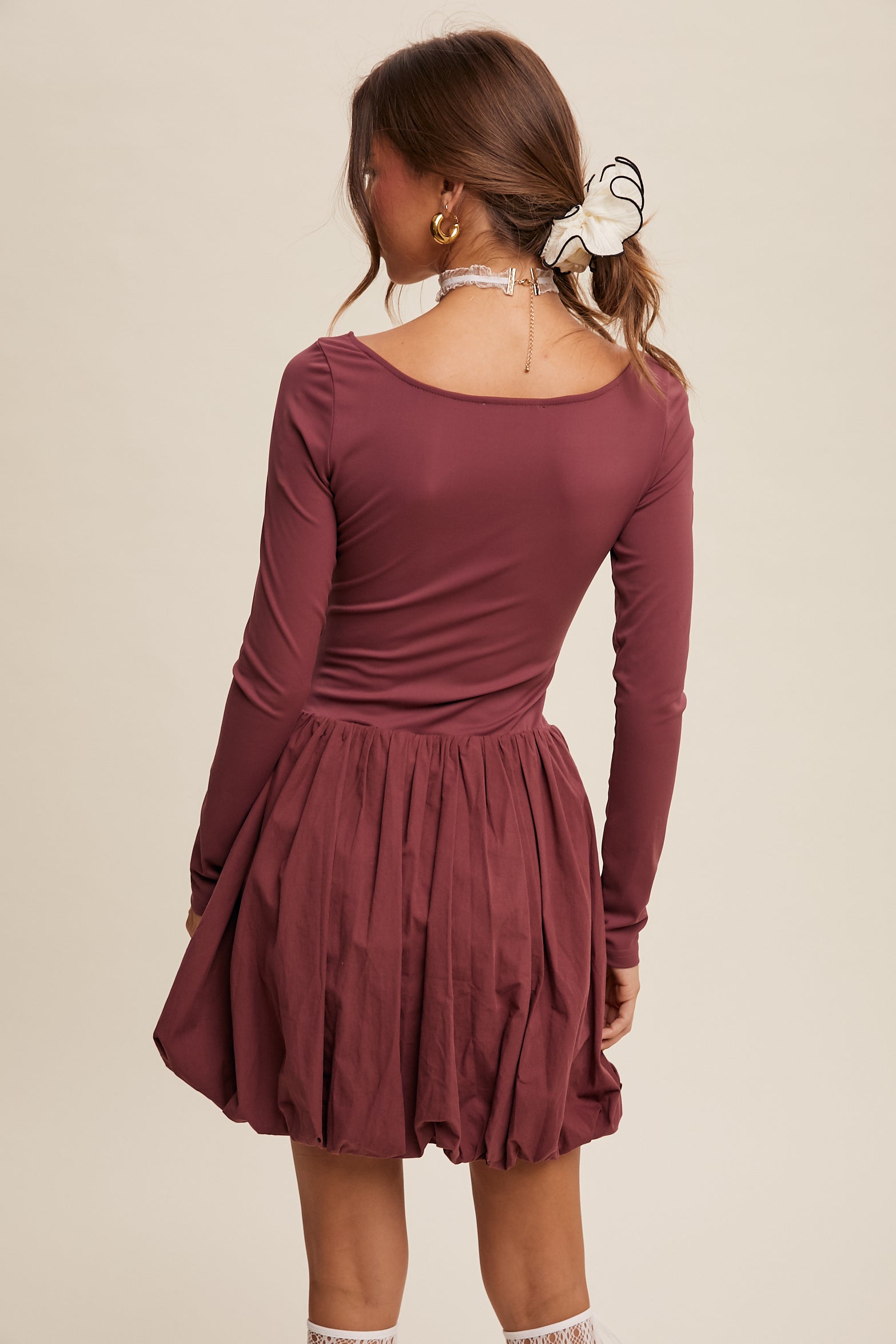 This dress features a square neckline, long sleeves, and a bubble skirt with a built-in romper liner. The top and shorts have a fitted, stretched design, and the skirt is made of cotton with a balloon layer. It comes in the color grape and is composed of 76% nylon and 24% spandex.