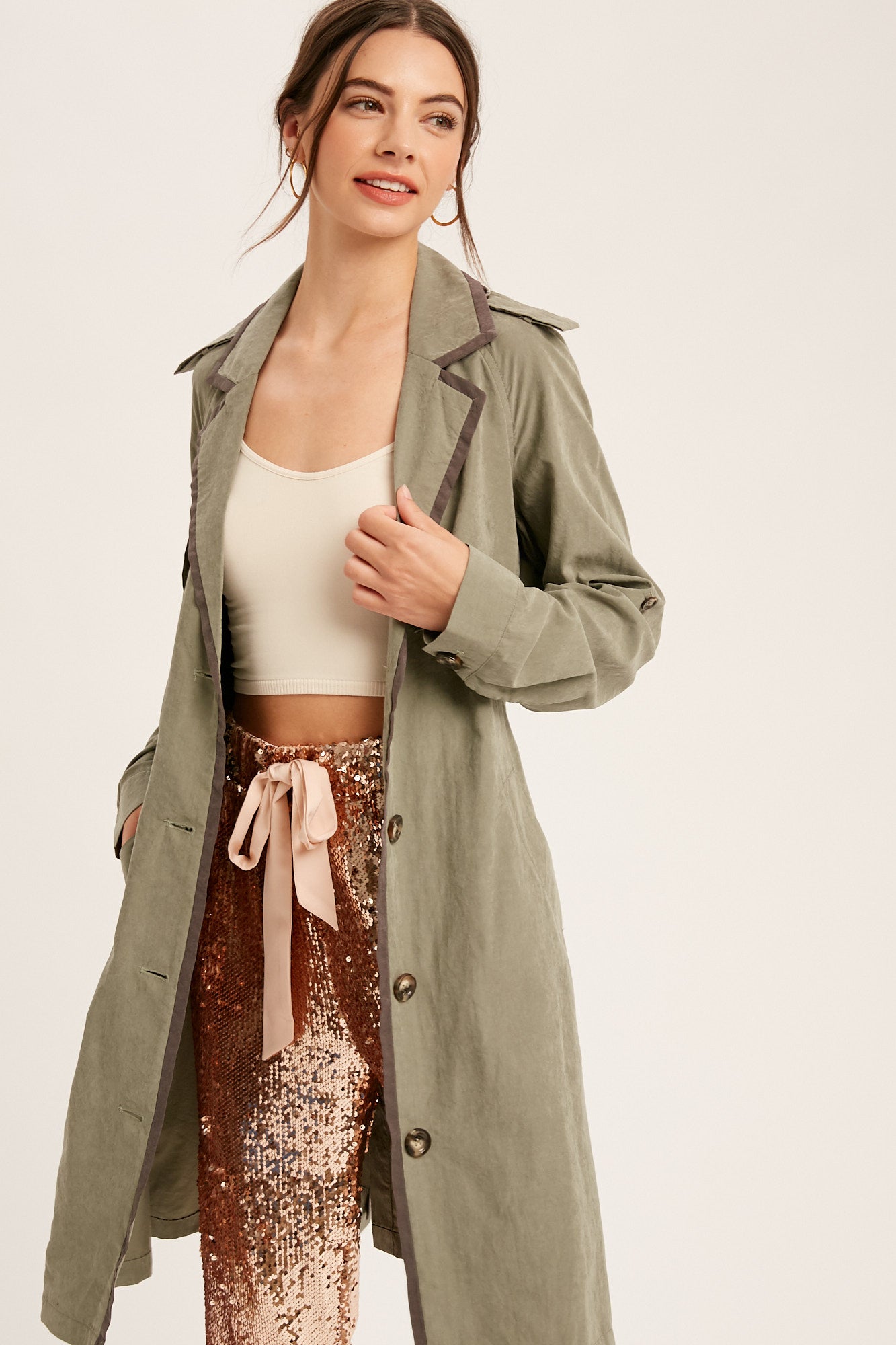 This textured trench coat features a notched collar, button down closure, and pockets. The adjustable cuffs and tie waist provide a customizable fit, while the contrast binding adds a stylish touch. Made of 100% polyester in Ash Olive color.