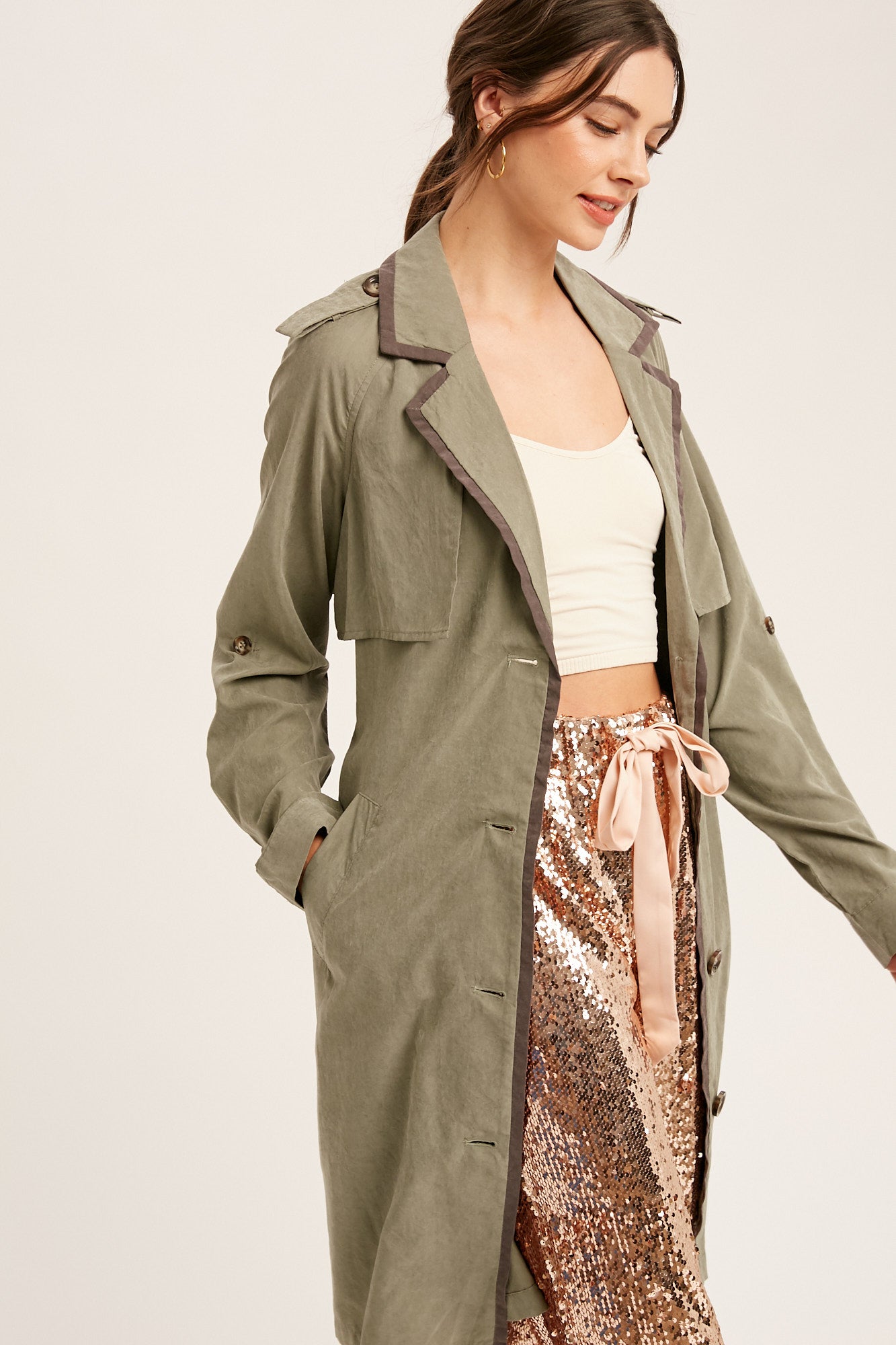 This textured trench coat features a notched collar, button down closure, and pockets. The adjustable cuffs and tie waist provide a customizable fit, while the contrast binding adds a stylish touch. Made of 100% polyester in Ash Olive color.