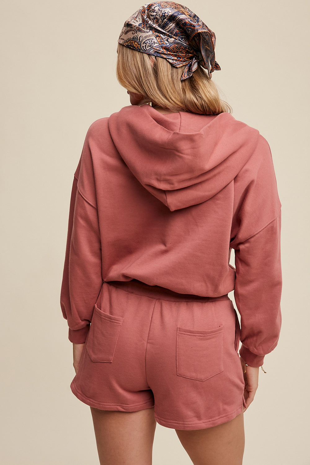 Expertly crafted from 100% cotton, this French terry hoodie romper features a low V neckline and long sleeves with elastic bands on the openings. The adjustable strap with elastic band on the waistband provides a comfortable fit, while the pocket on the side front bottom shorts adds functionality. This piece is completed with a clean hem and is available in a rich Deep Rose color.