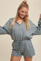 Expertly crafted from 100% cotton, this French terry hoodie romper features a low V neckline and long sleeves with elastic bands on the openings. The adjustable strap with elastic band on the waistband provides a comfortable fit, while the pocket on the side front bottom shorts adds functionality. This piece is completed with a clean hem and is available in a Sage color.