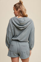 Expertly crafted from 100% cotton, this French terry hoodie romper features a low V neckline and long sleeves with elastic bands on the openings. The adjustable strap with elastic band on the waistband provides a comfortable fit, while the pocket on the side front bottom shorts adds functionality. This piece is completed with a clean hem and is available in a Sage color.