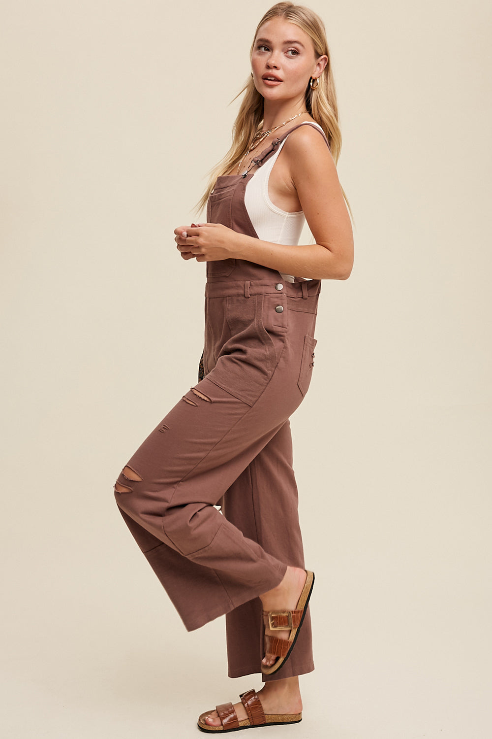 Crafted from 100% cotton, the Distressed French Terry Overalls feature a relaxed fit with distressed detailing, adjustable straps with buckle closures, and a convenient front pouch pocket. Complete with a waistband and belt loop, low back drop, and patch detailing on the bottom pants, this versatile piece is finished with a clean hem. Available in Mocha.