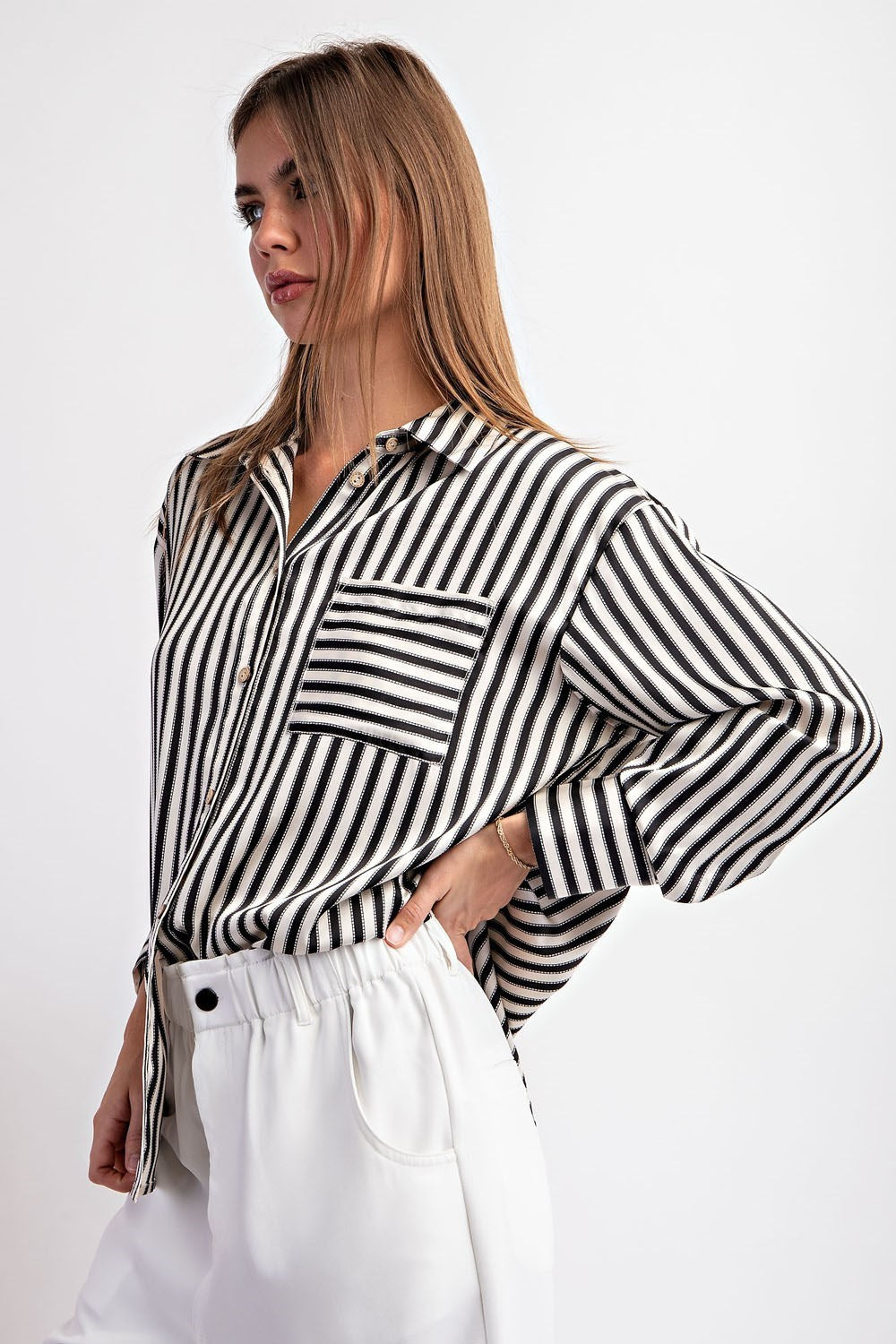 This cropped-length top is made from 100% polyester and boasts a collared neckline, button-down front, and two chest pockets. It also features a bottom hem tie closure and buttoned cuffs for a sophisticated touch.