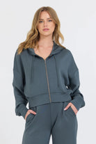 The Mountain Grey Cloud Fleece Crop Zip boasts an adjustable drawstring hood and a zip-up design, crafted from a blend of 49% Modal, 45% Polyester, and 6% Spandex for a comfortable and stylish fit.