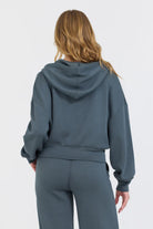 The Mountain Grey Cloud Fleece Crop Zip boasts an adjustable drawstring hood and a zip-up design, crafted from a blend of 49% Modal, 45% Polyester, and 6% Spandex for a comfortable and stylish fit.