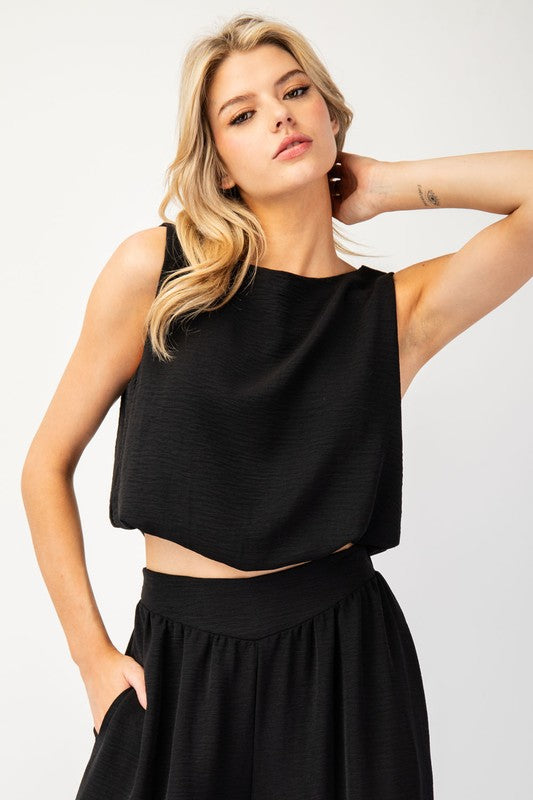 Crafted from 100% polyester, this solid sleeveless crop top boasts a rounded neckline, gathered bottom, and cropped length. Its slight bubble body silhouette is sure to elevate any outfit.