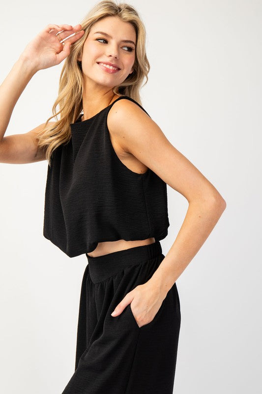 Crafted from 100% polyester, this solid sleeveless crop top boasts a rounded neckline, gathered bottom, and cropped length. Its slight bubble body silhouette is sure to elevate any outfit.